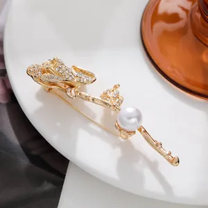 Macro view of a golden rose brooch with shimmering rhinestones and a white pearl