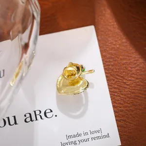 Macro view showing the back clasp and texture of an elegant gold apple brooch pin