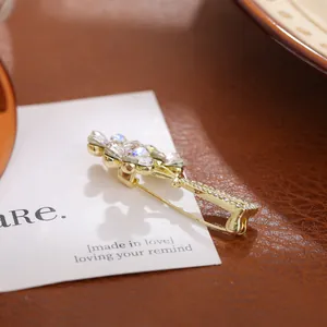 Close-up of elegant crystal vase brooch with sparkling gemstones on gold base.