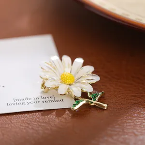 Detailopname van een delicate madeliefjesbroche met witte bloembladen en gouden steel
