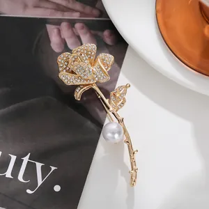 Exquisite golden rose brooch adorned with sparkling rhinestones and a lustrous pearl detail