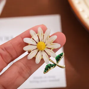 Close-up detail van een charmante witte madeliefjesbroche met levendige groene bladeren