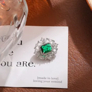 Detalle de broche de lujo con cristal verde esmeralda rectangular y halo resplandeciente
