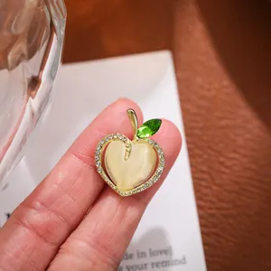 Close-up of an elegant apple-shaped brooch with cat eye stone and sparkling crystals