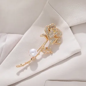 Close-up of elegant gold-toned rose brooch with shimmering crystals and white pearl