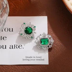 Primer plano detallado de dos broches de cristal de lujo con piedras verdes.