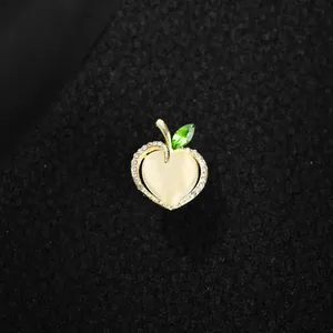 Detailed macro shot of an elegant apple-shaped brooch with heart opal and green leaf.