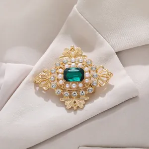 Detailed macro view of vintage emerald brooch with pearls pinned on cream suit lapel