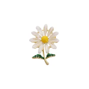 Elegante witte madeliefje bloem broche met geel hart en groene bladeren op goud