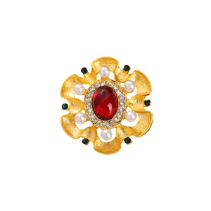Broche dorée baroque vintage avec pierre précieuse rouge et perles sur fond blanc