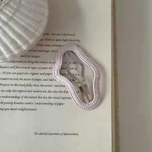 Detailed view of a pink wavy fabric hair clip with stitching on an open vintage book