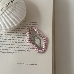 Detailed view of a pink and white gingham checkered wavy hair clip on a vintage book
