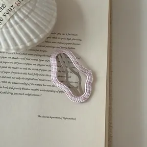 Detail shot of pink checkered wavy hair clip on vintage book page background.