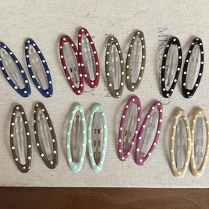 Vue rapprochée de huit paires de barrettes à pois ovales colorées sur tissu en lin