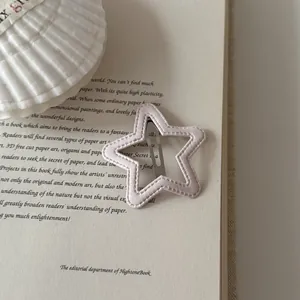 Detailed macro view of a star-shaped pink fabric-wrapped BB hair clip on a vintage book page