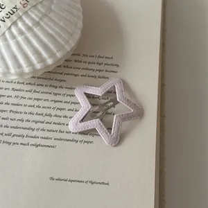 Close-up of a pink star-shaped leather hair clip displayed on an open vintage book