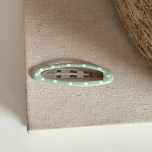 Vue détaillée d'une pince à cheveux BB ovale à pois vert menthe sur texture