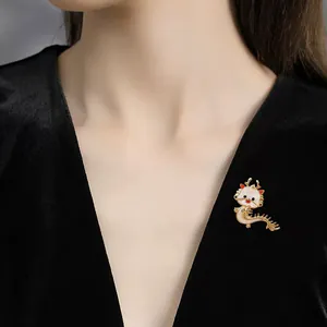 Detailansicht einer niedlichen Drachenbrosche aus Emaille an einem schwarzen Samtkleid