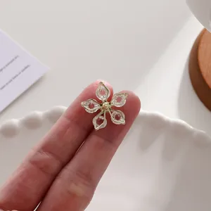 Detailansicht einer eleganten Blumenbrosche mit facettierten Kristallen und Goldrahmen.