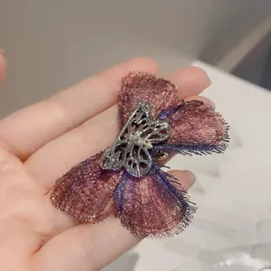 Gros plan d'une broche papillon brodée vintage avec ailes dégradées violettes et épingle métal