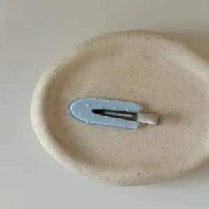 Close-up of light blue hair clip with heart pattern on a textured stone tray