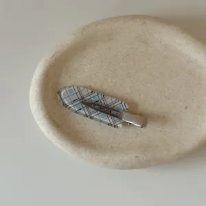 Close-up macro view of the blue plaid pattern on an elegant no-trace hair clip