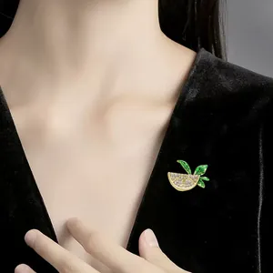Detailed view of a sparkling lemon slice brooch with green leaves on black velvet