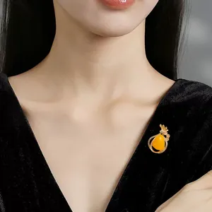 Elegant golden brooch with yellow teardrop stone shown on a black velvet dress accessory