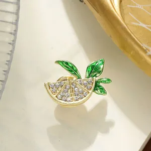 Detailed view of a golden fruit slice brooch with shimmering rhinestones and green leaves