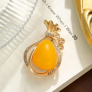 Detailed view of gold-tone money bag brooch with large yellow stone and pave crystals