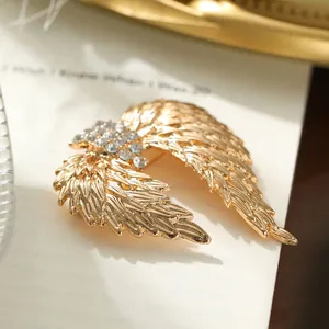Detailed macro view of a vintage golden angel wing brooch with sparkling rhinestones