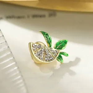 Close-up of a sparkling lemon slice brooch with enamel green leaves and rhinestones.