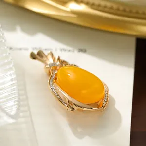 Close-up of golden alloy brooch with large oval yellow stone and crystal accents
