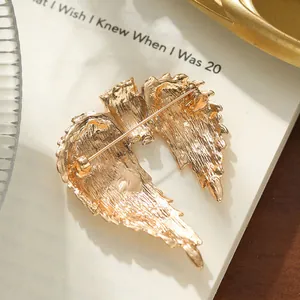 Detail of vintage gold wing feather brooch showing back pin mechanism and texture