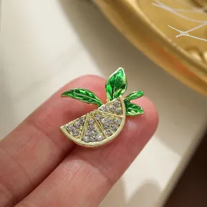 Macro view of a sparkling fruit slice brooch featuring green leaves and rhinestones.