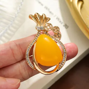 Close-up of elegant gold-toned alloy brooch with yellow stone and rhinestones