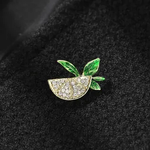 Close-up of cute lemon slice brooch with rhinestones and green leaves on black fabric
