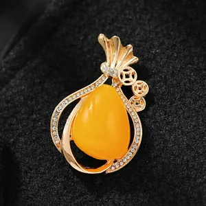 Macro detail view of a gold money bag brooch featuring yellow stone and shiny rhinestones.