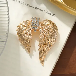 Vintage gold angel wing brooch with sparkling rhinestones on a book background