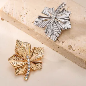 Detailansicht eleganter Ahornblatt-Broschen in Gold und Silber mit funkelnden Kristallen