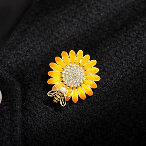 Detail shot of a yellow enamel daisy brooch with a small bee and rhinestone center.