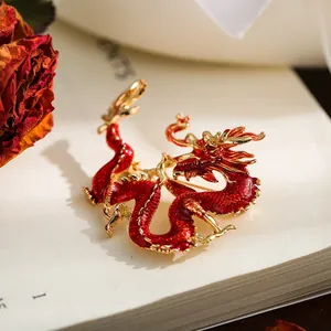 Detalle macro de un broche de dragón chino en esmalte rojo y aleación de oro en libro