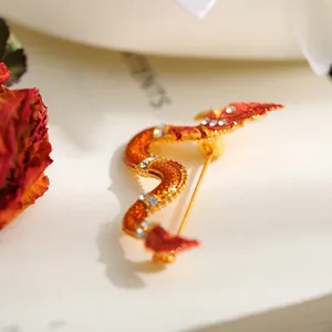 Close-up of golden alloy dragon brooch with rhinestones and orange enamel detail