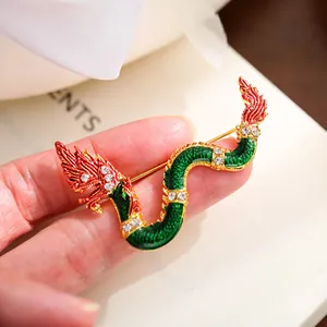 Detailed macro view of the dragon-shaped brooch with green enamel and crystal accents.