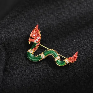 Close-up of an ornate dragon brooch with green scales and sparkling crystals on black fabric.