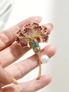 Gros plan détaillé sur l'élégante broche œillet avec strass colorés et une perle.