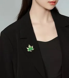 Eleganter grüner Ahornblatt-Brosche mit kleinem Strassstein auf einem schwarzen Blazer.