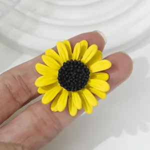 Detail van een felgele zonnebloem broche met een zwart getextureerd hartje.