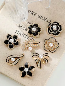Elegante schwarze Kamelien- und Rosenbroschen mit Perlen und Golddetails.