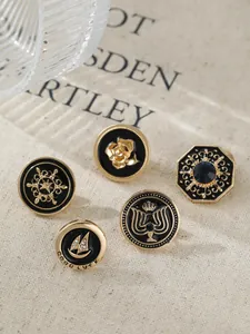 Detailed view of five vintage gold-toned lapel pins with black enamel designs